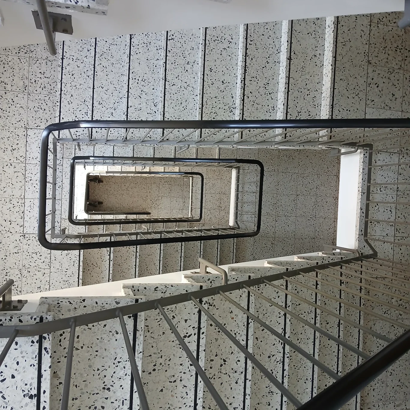 Sicht auf eine spiralförmige Treppe mit hellen Stufen und Geländer.