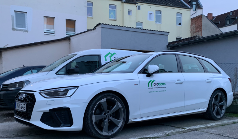 Weißer Audi Sportwagen neben einem weißen Lieferwagen Caddy SA vor einem Gebäude, beide Wagen mit dem Logo von Proclean versehen.