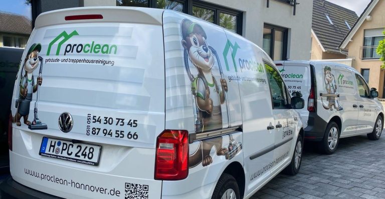 Zwei Lieferwagen, einer weiß mit Logo, geparkt auf einem gepflasterten Bereich.